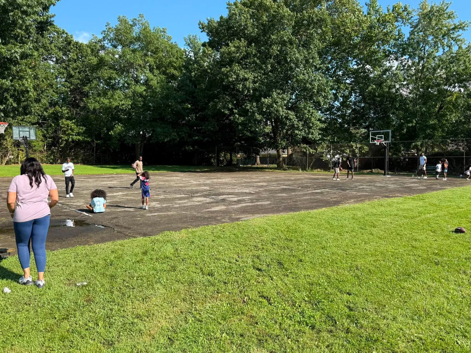 Children and adults playing on the cracked asphalt court on the church grounds
